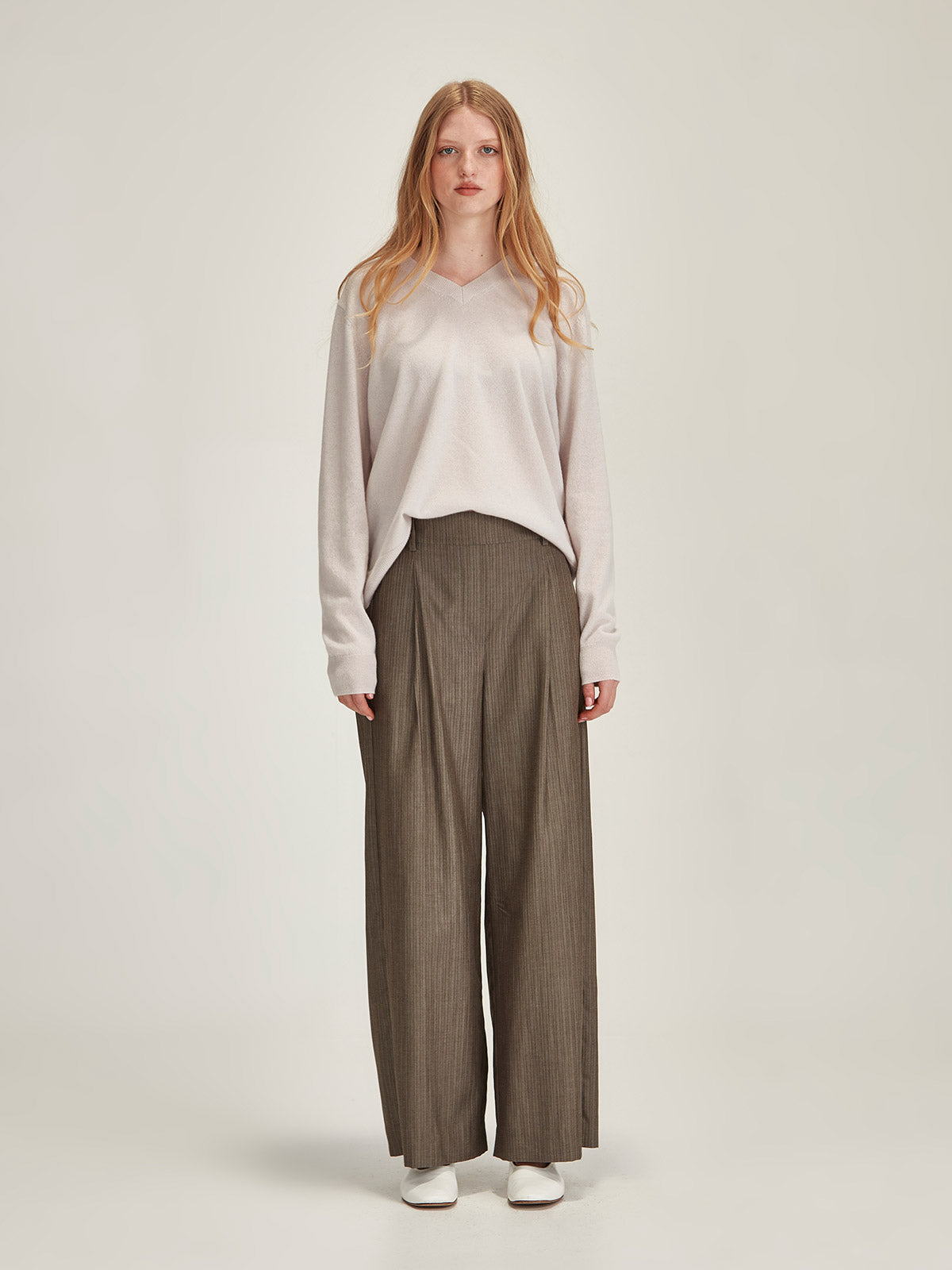 Woman wearing Caroline Sills Lucy Cashmere VNeck Sweater in Vapour beige and Brook Stripe Pant against grey backdrop