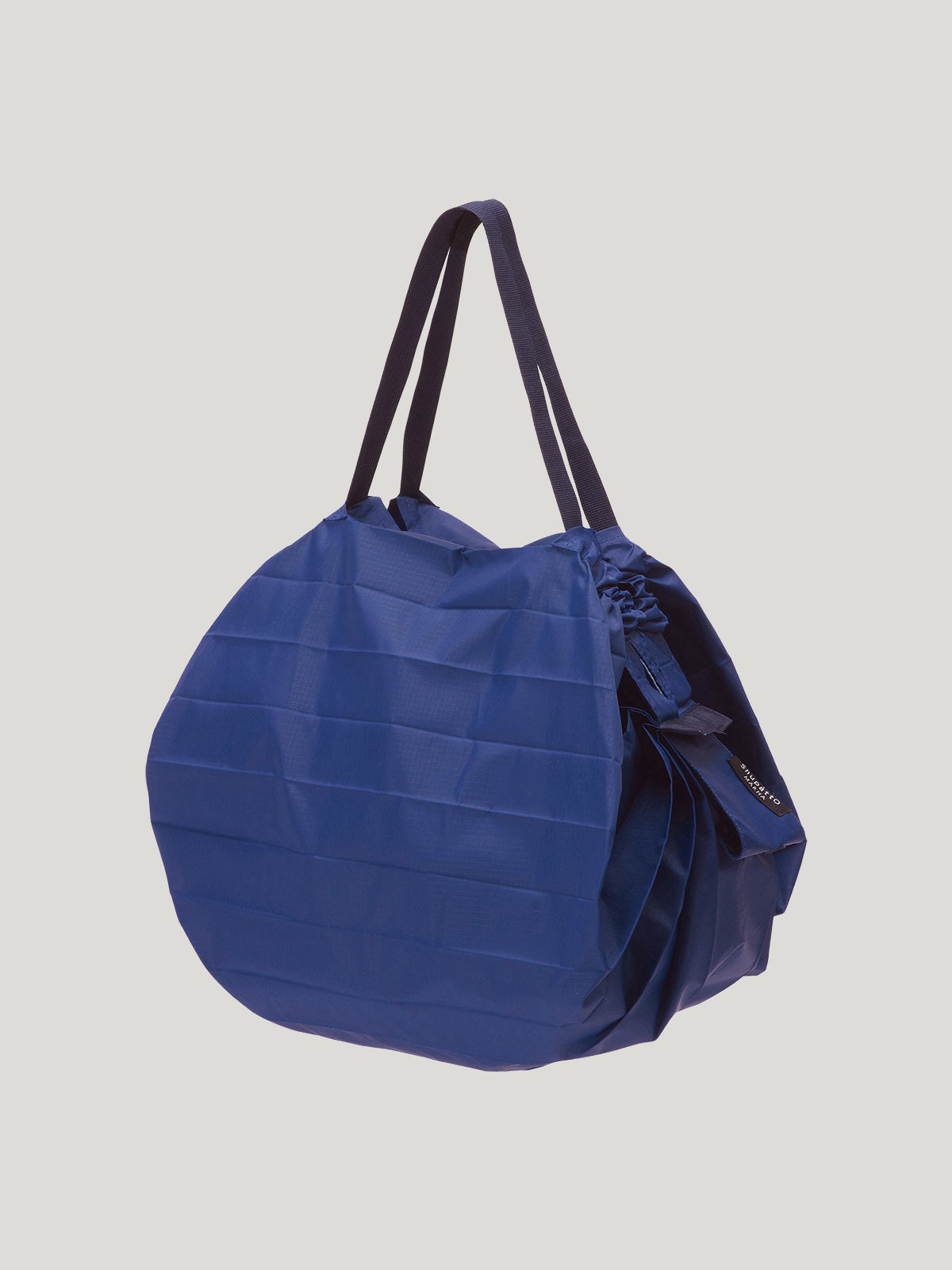 Foldable, reusable shopping bag in solid blue colour on a grey background.