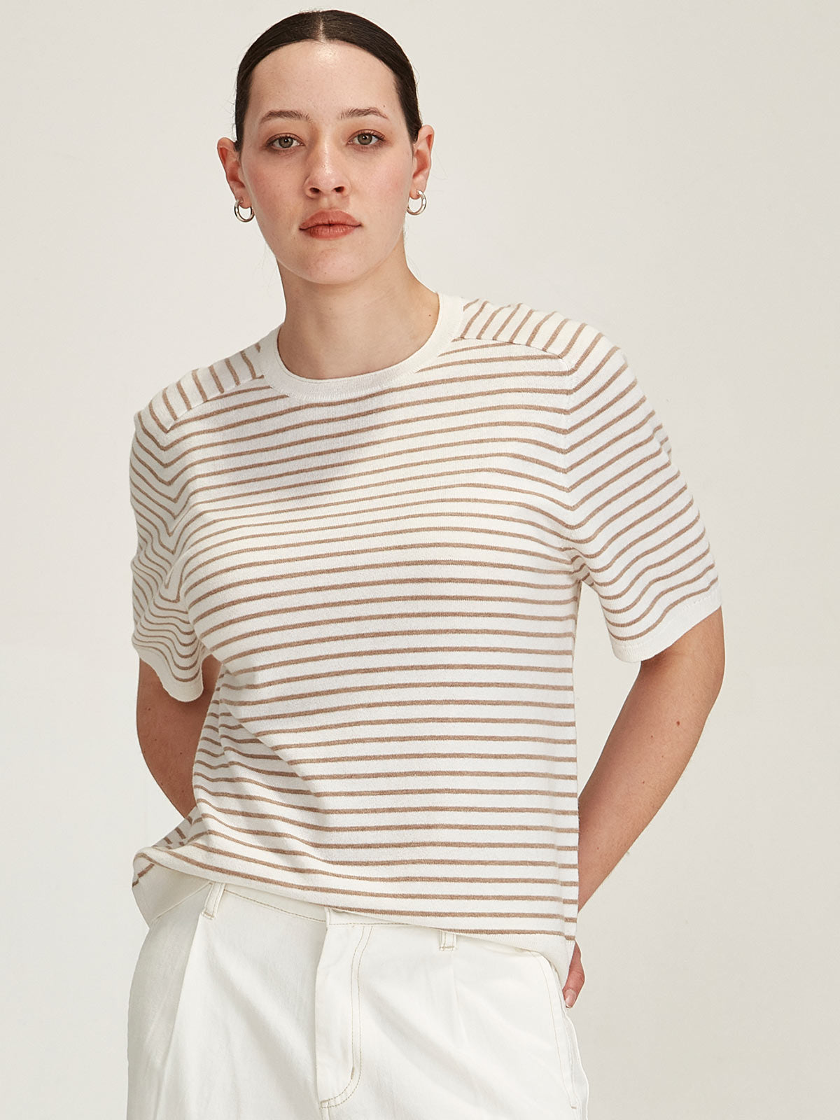 woman wearing Sills Cecilia Stripe knitted Tee t-shirt in off white and beige stripe on grey background
