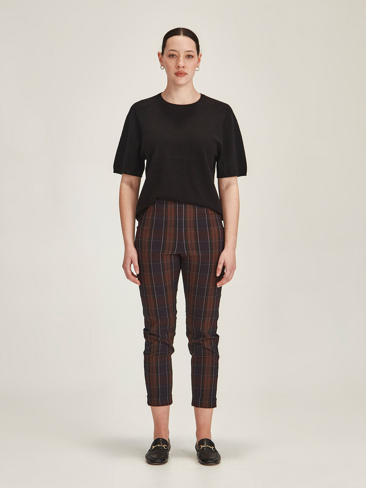 woman wearing a black Sills Cecilia knitted Tee t-shirt and plaid Hepburn legging pant on grey background