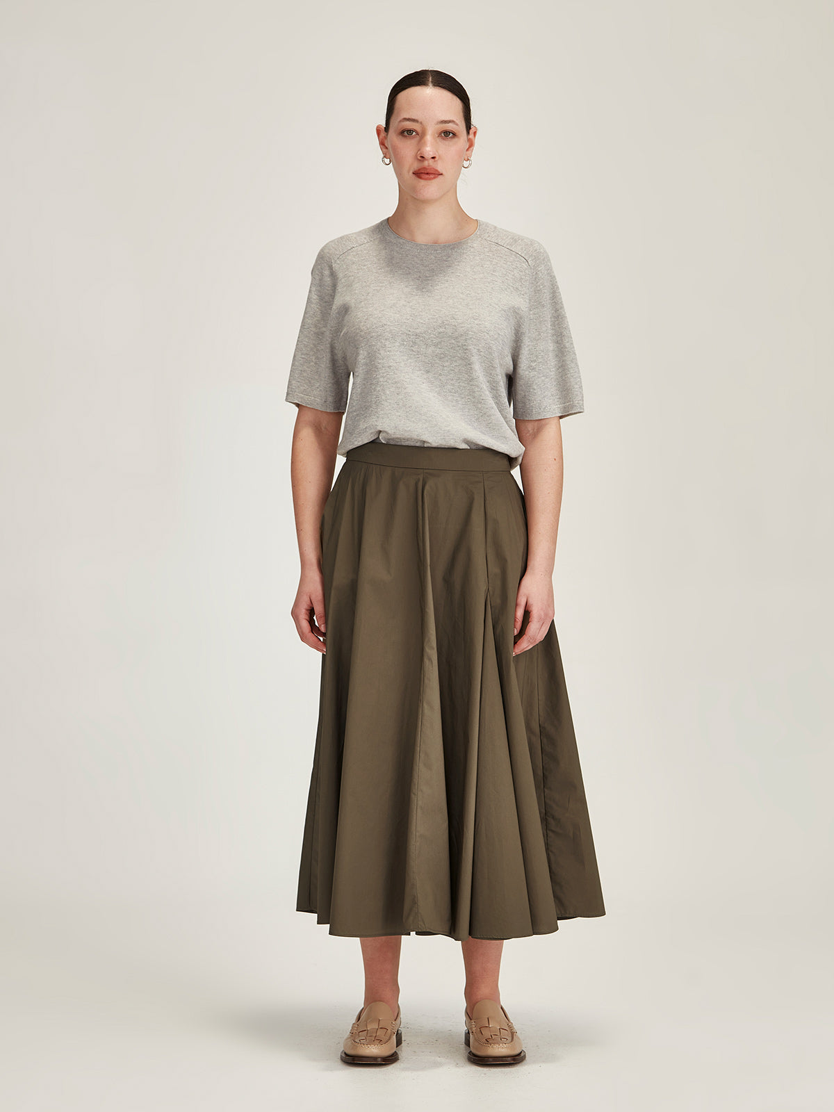 woman wearing a grey Sills Cecilia knitted Tee t-shirt and khaki Zaiya godet midi skirt on grey background