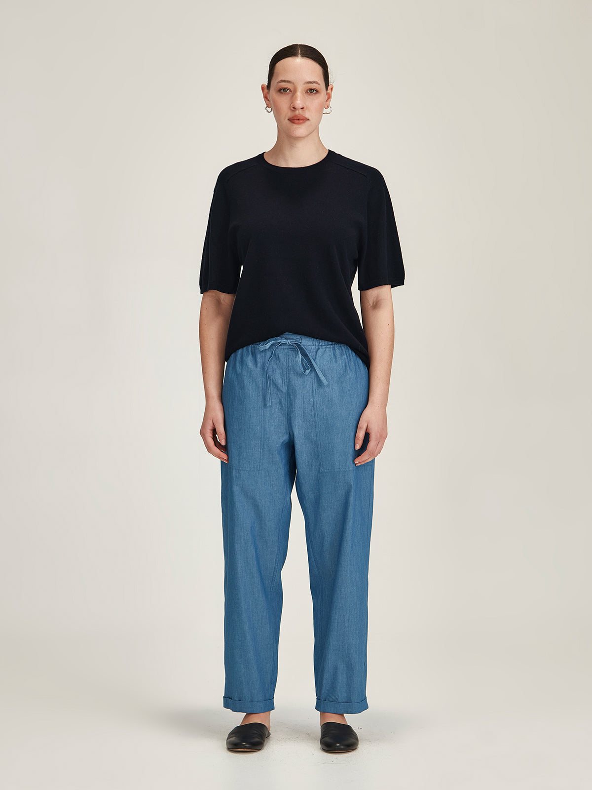 woman wearing a navy Sills Cecilia knitted Tee t-shirt and chambray denim Serena cropped pants on grey background