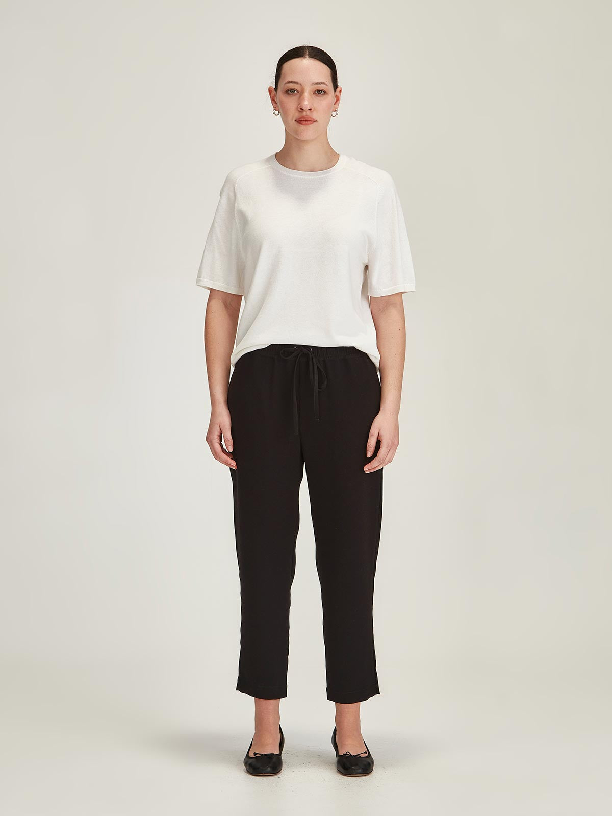 woman wearing a off white Sills Cecilia knitted Tee t-shirt and black cropped Romily pants on grey background