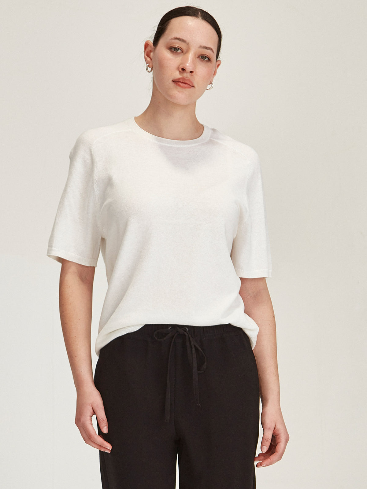 close up of a woman wearing a off white Sills Cecilia knitted Tee t-shirt on grey background