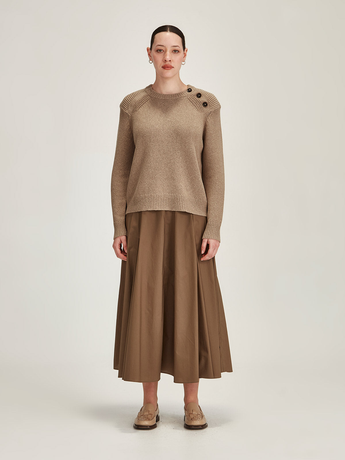 woman wearing Sills camel Colette merino wool/cotton blend sweater with bronze Zaiya midi skirt against grey background