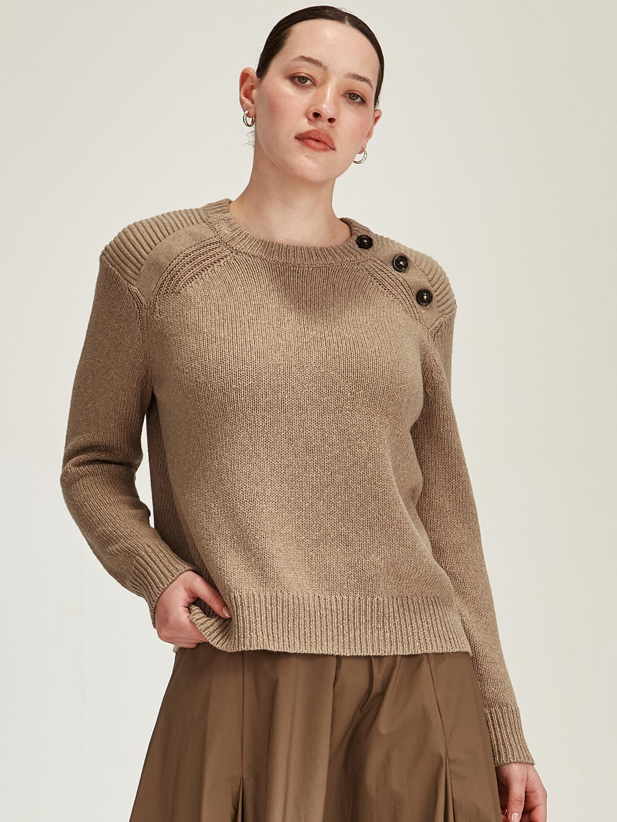 close up of woman wearing camel Sills merino/cotton knitted Colette jumper with buttons on shoulder against grey background