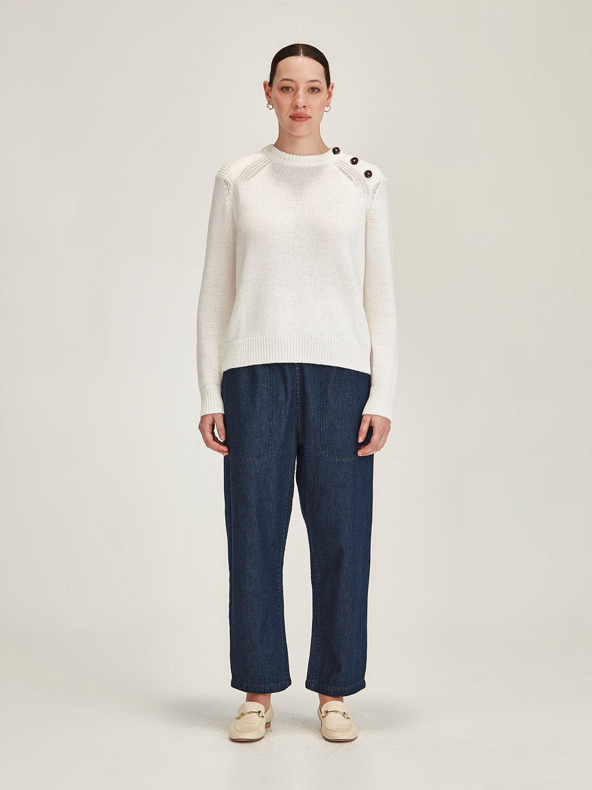 woman wearing Sills off white Colette merino wool/cotton blend sweater with Ginza Drawstring jeans against grey background