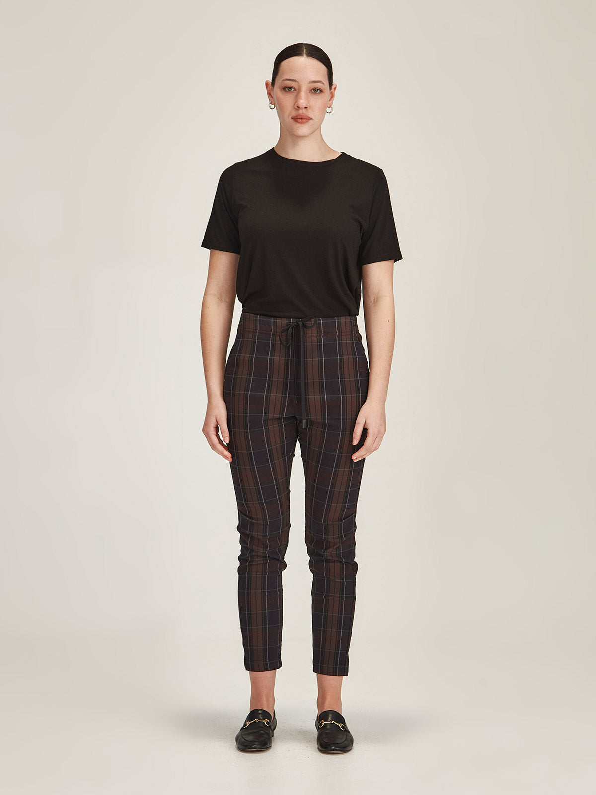 woman against grey background wearing Sills black merino blend Lena Tee with chocolate plaid Emily Joggers