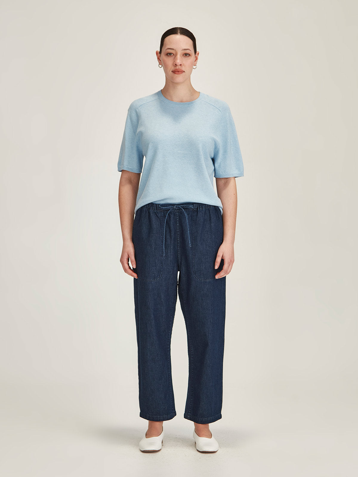 woman wearing Sills dark denim Ginza Drawstring cropped Jean and baby blue Cecilia knit t-shirt on grey background