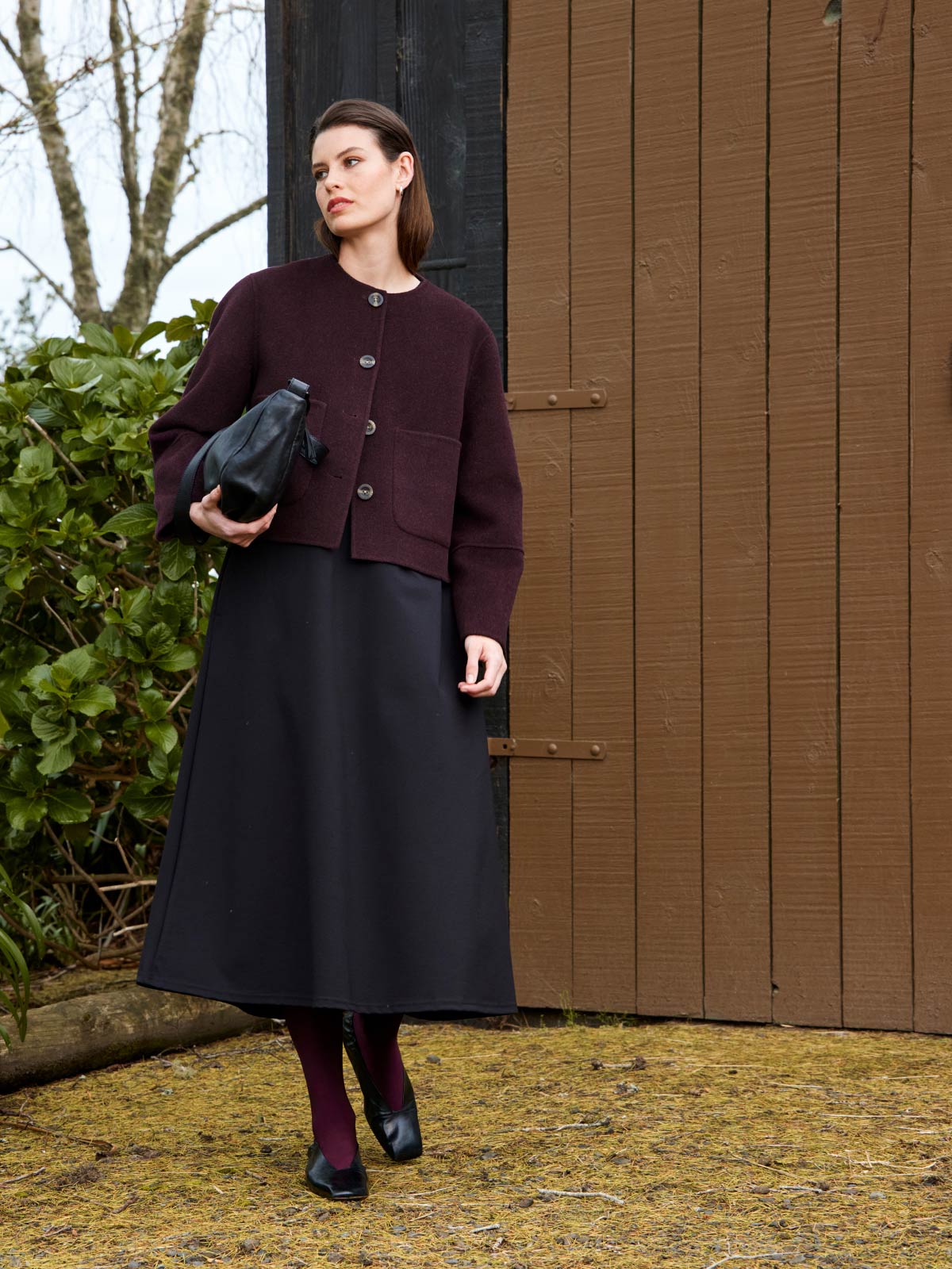 Woman outdoors wearing Sills Emiko wool and cashmere blend Jacket in plum with Tula Dress and Juju & Co Stevie Sling