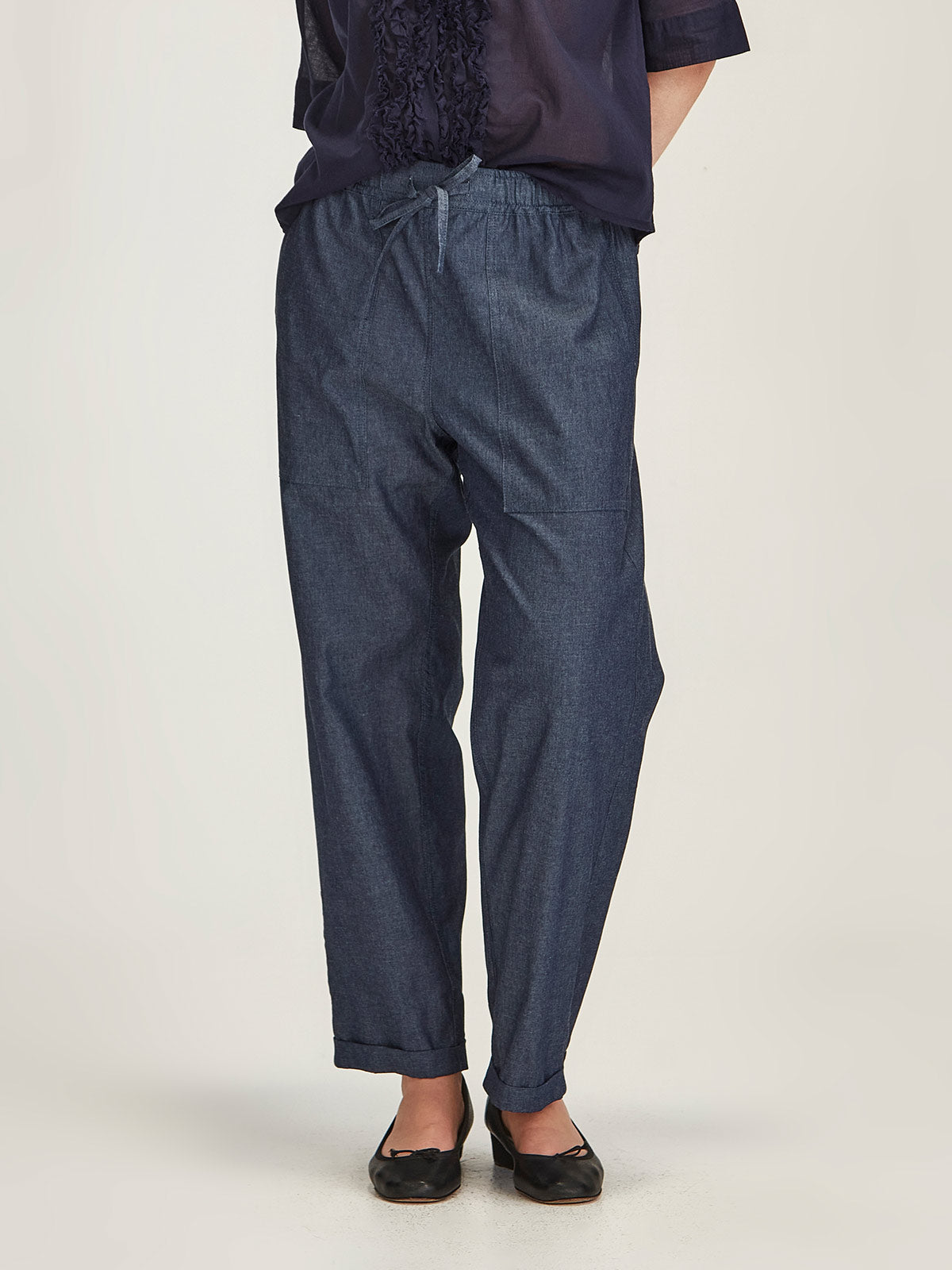 Close up of woman wearing Sills dark indigo Serena Chambray Pant with drawstring waist in front of a grey background