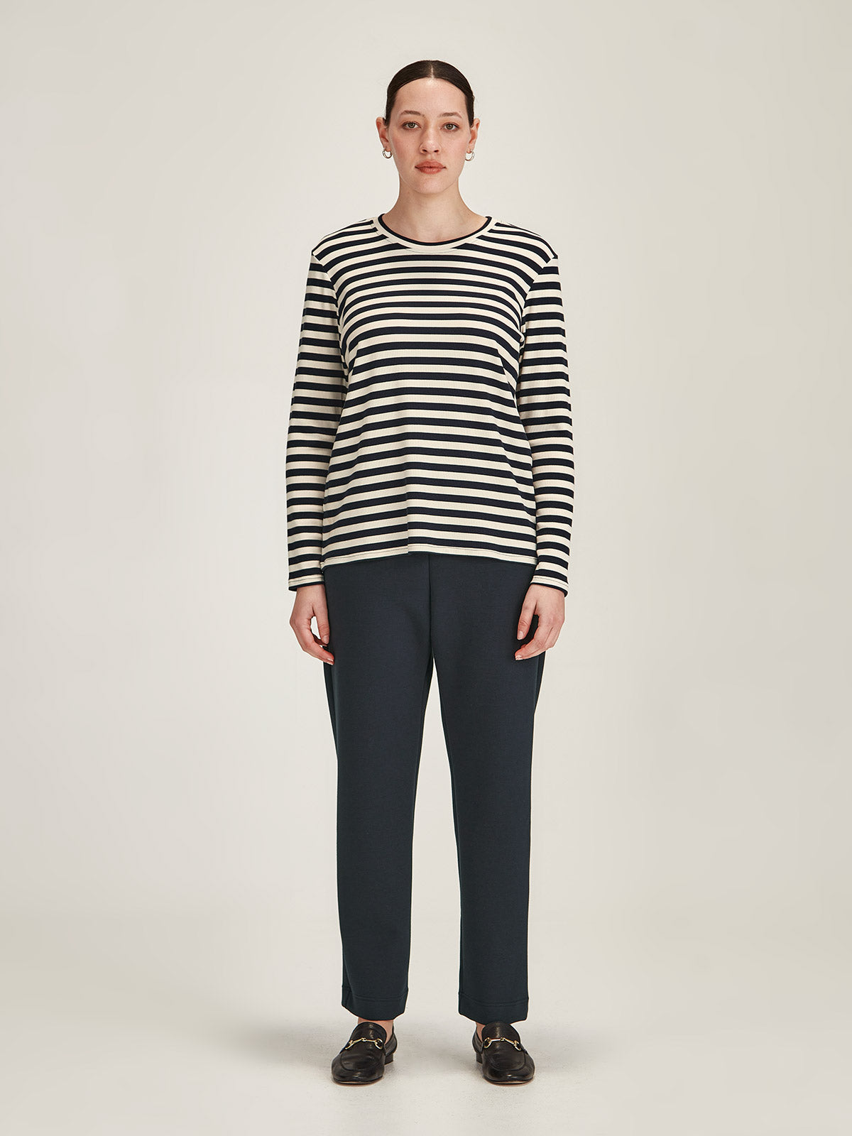 woman against grey background wearing Sills navy/ivory striped crew neck long sleeve top and navy Kathryn scuba pants