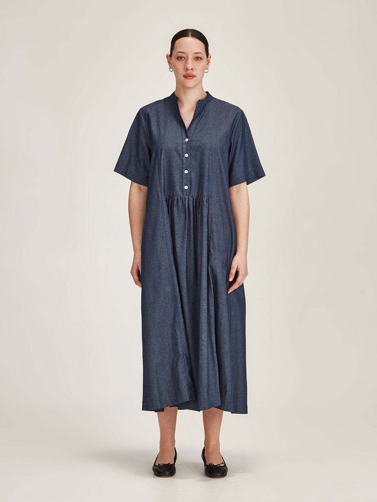 Woman in front of grey background wearing a dark denim Sills Vicky Chambray short sleeve, drop waist midi dress