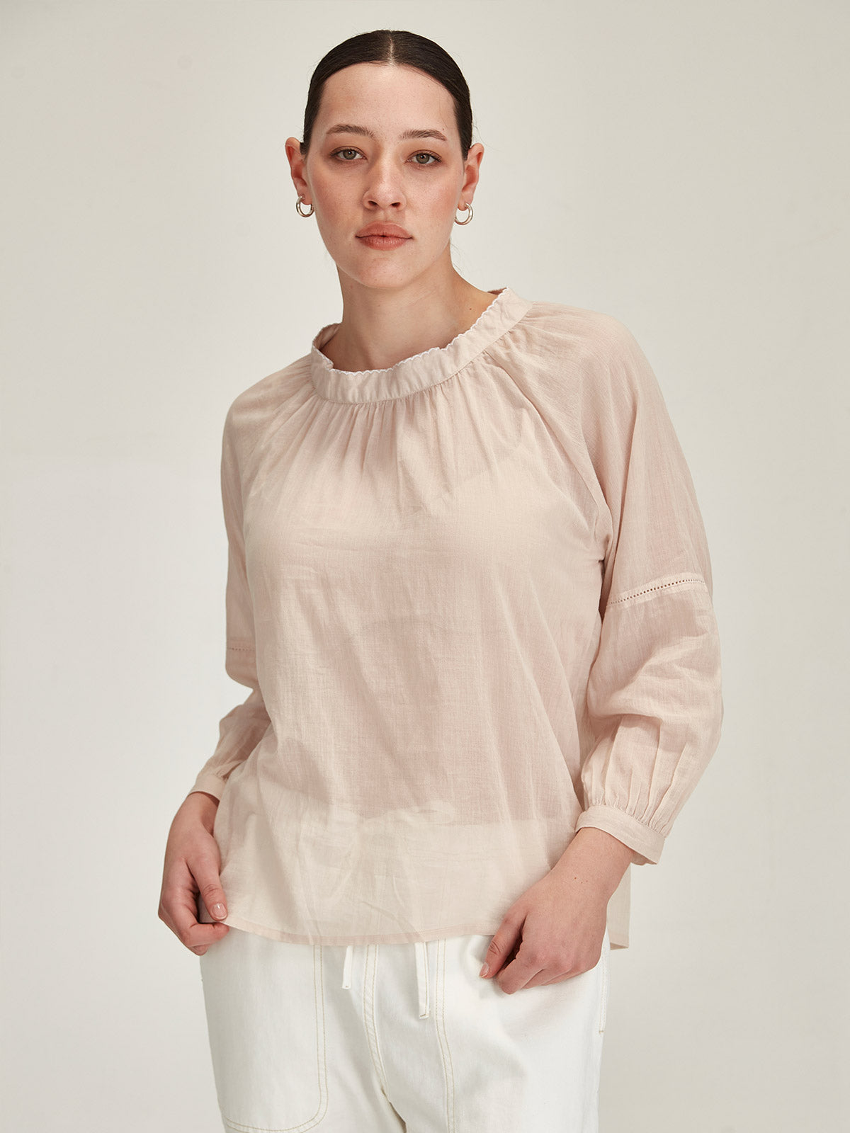 Model wearing a Sills beige organic cotton voile Hana Top with white embroidery against grey background