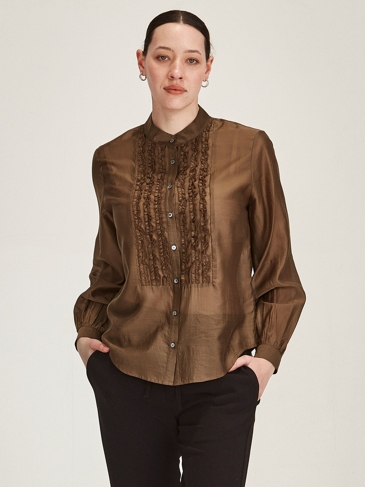 Close up of woman wearing Cinnamon brown Sills Ami Shirt with ruffle detail front in front of grey background
