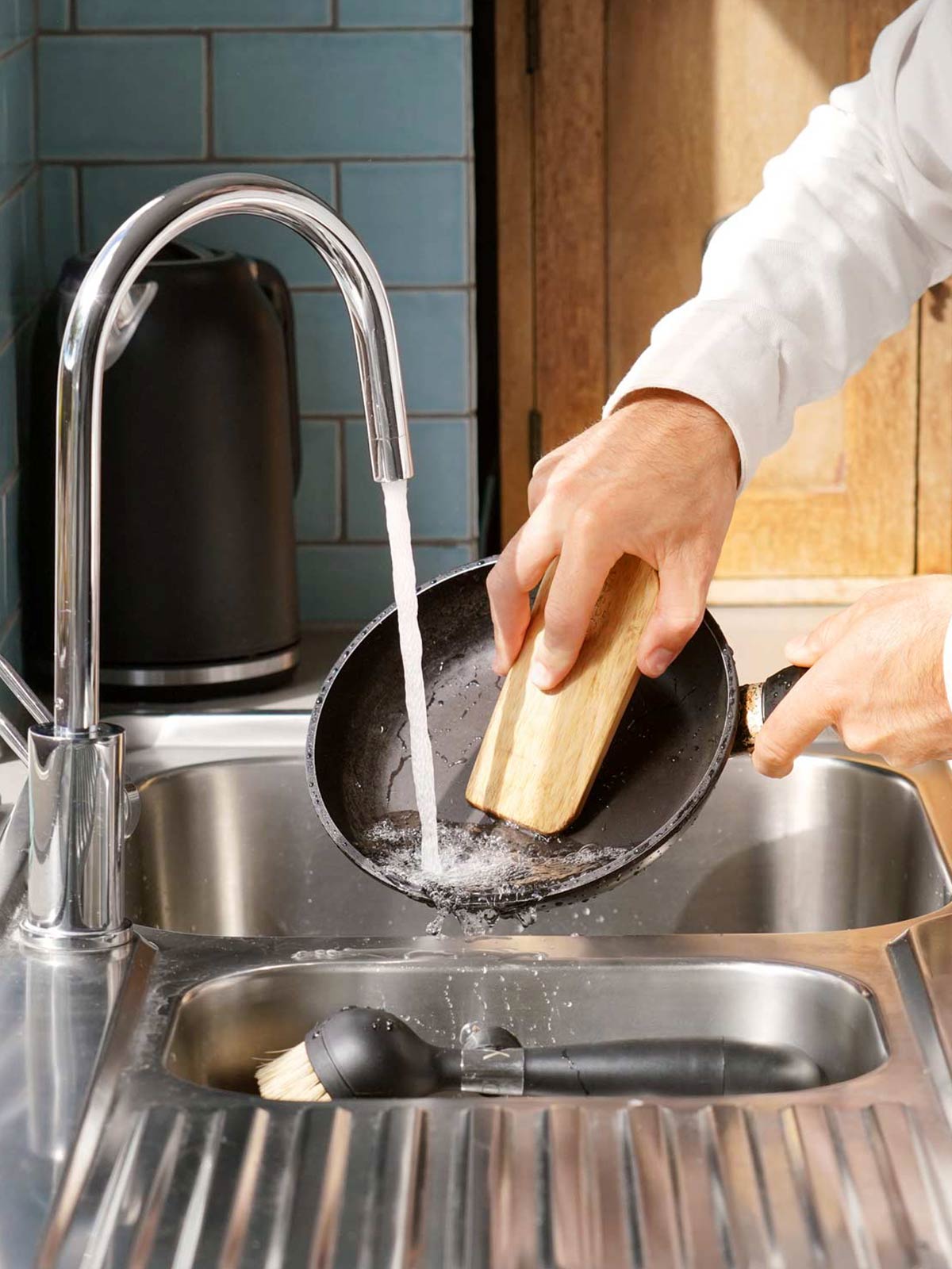 The ONE BRUSH by Yeseco - Black eco-friendly dish brush with magnetic wall mount demonstration, showing space-saving storage solution for sustainable kitchen scrubber with detachable sisal fibre head.