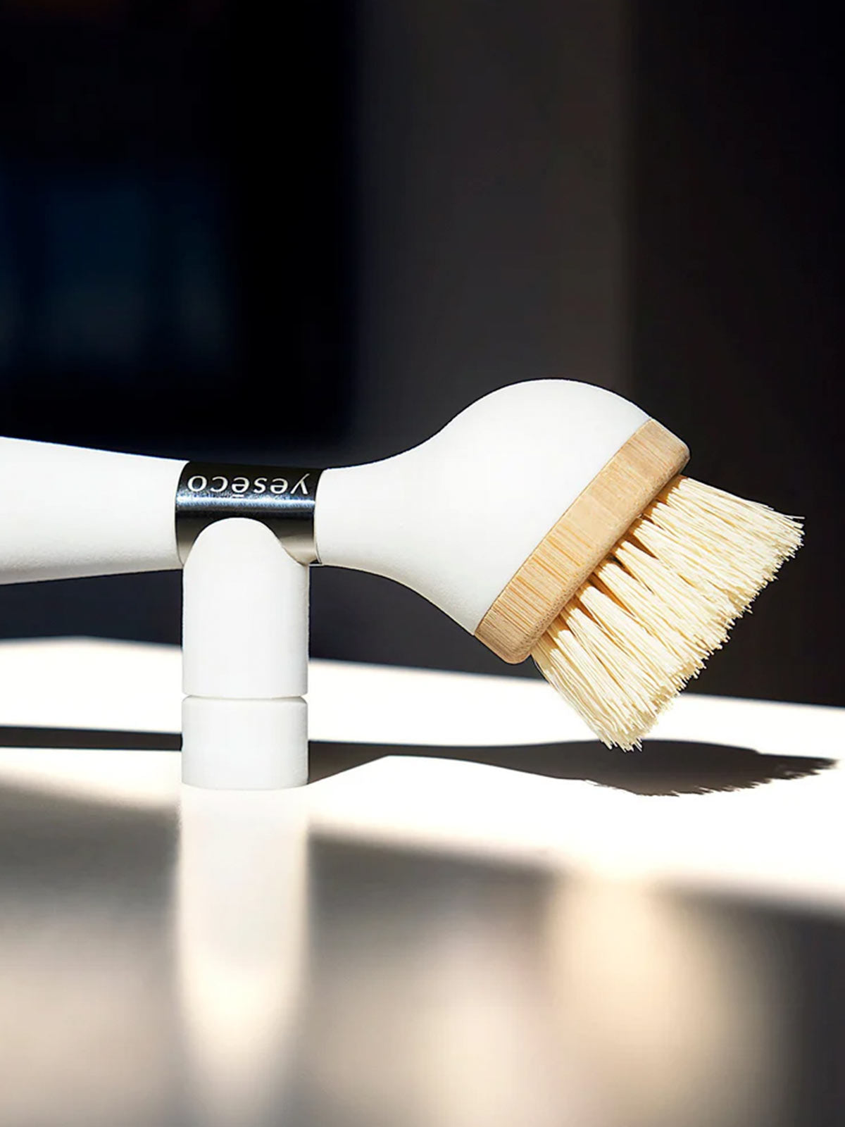 The ONE BRUSH by Yeseco - Close-up side view of white eco-friendly dish brush showing magnetic wall mount and detachable sisal fiber head, sustainable kitchen cleaning tool with integrated soap dispenser handle.