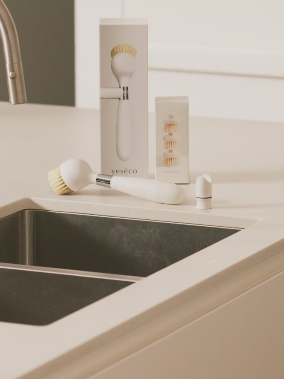The ONE BRUSH by Yeseco - White eco-friendly dish brush styled in a modern kitchen setting, showcasing minimalist design with a magnetic mount that easily clips the brush into a kitchen sink.
