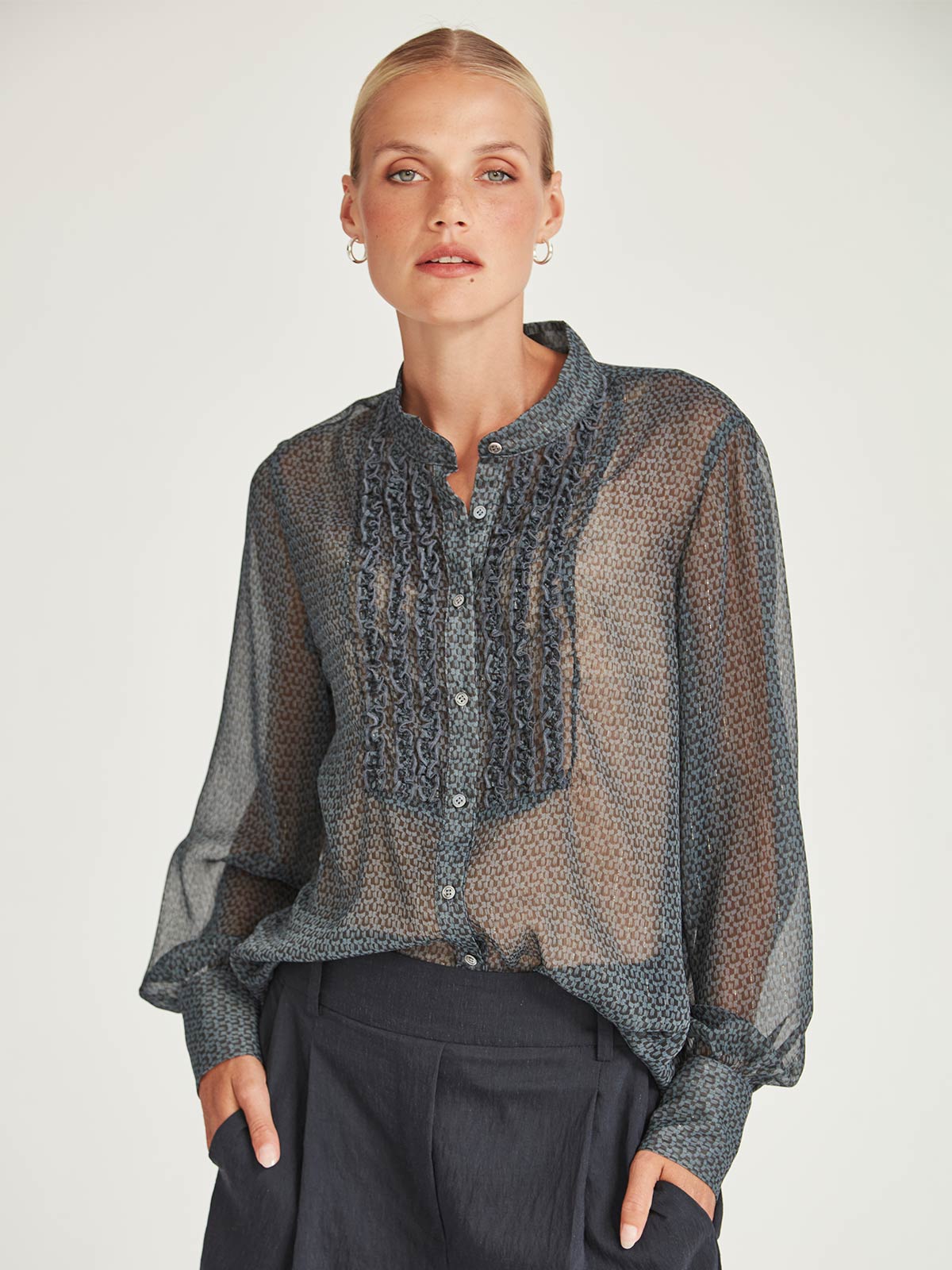 Close-up front view of the Caroline Sills Dauphine Blouse in navy print, featuring a Mandarin collar neckline, ruffle trim detail on the bust, and sheer long sleeves. 