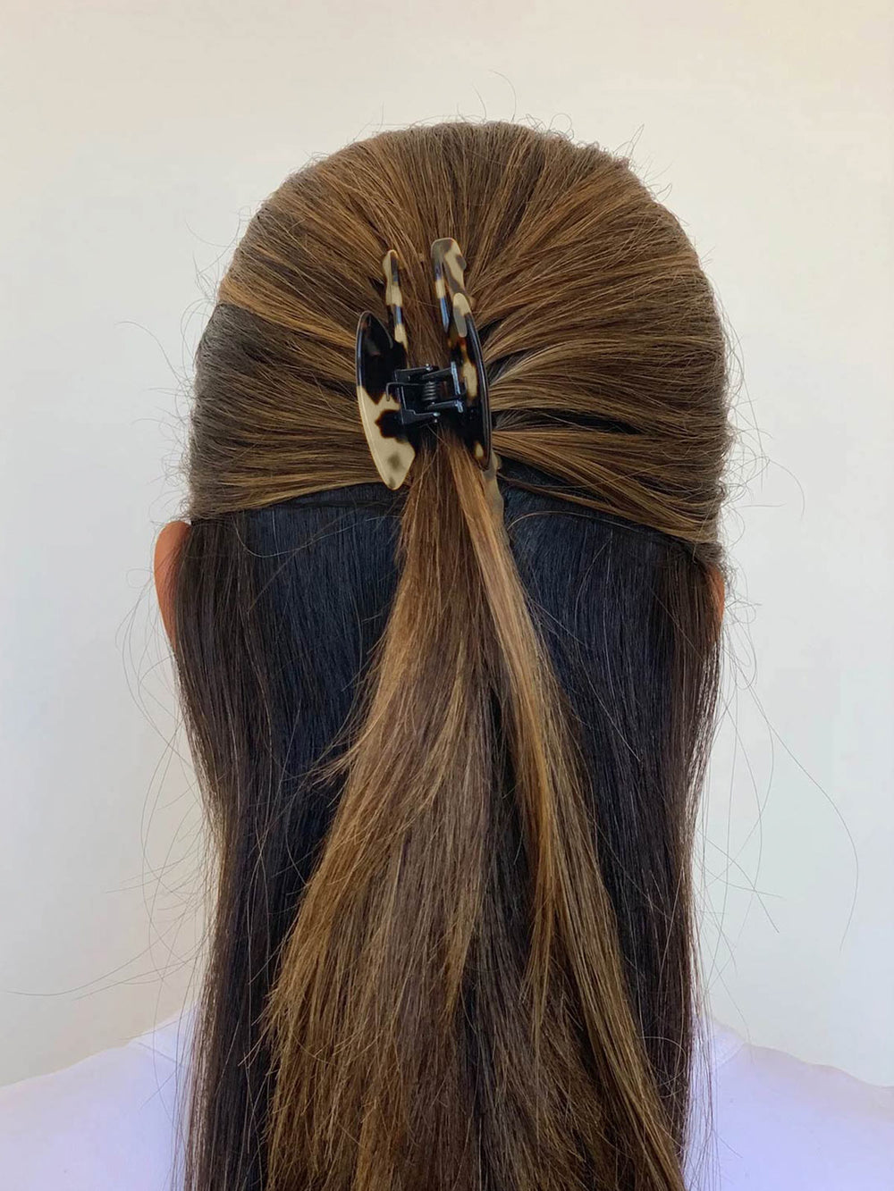 Half-up hairstyle secured with a tortoiseshell hair clip