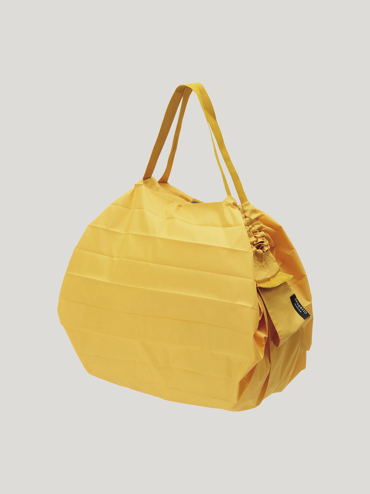 Foldable, reusable shopping bag in solid mustard yellow colour on a grey background.