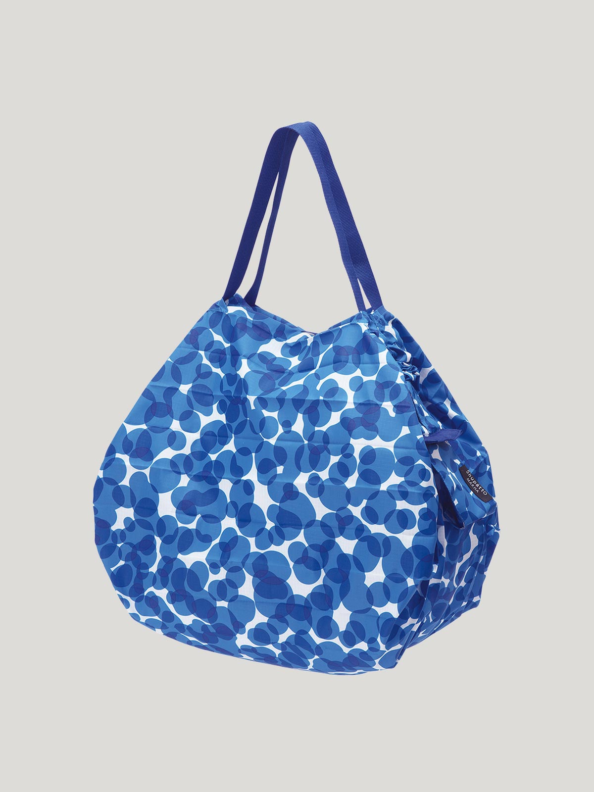 Foldable, reusable shopping bag with a blue overlapping dot design on a grey background.
