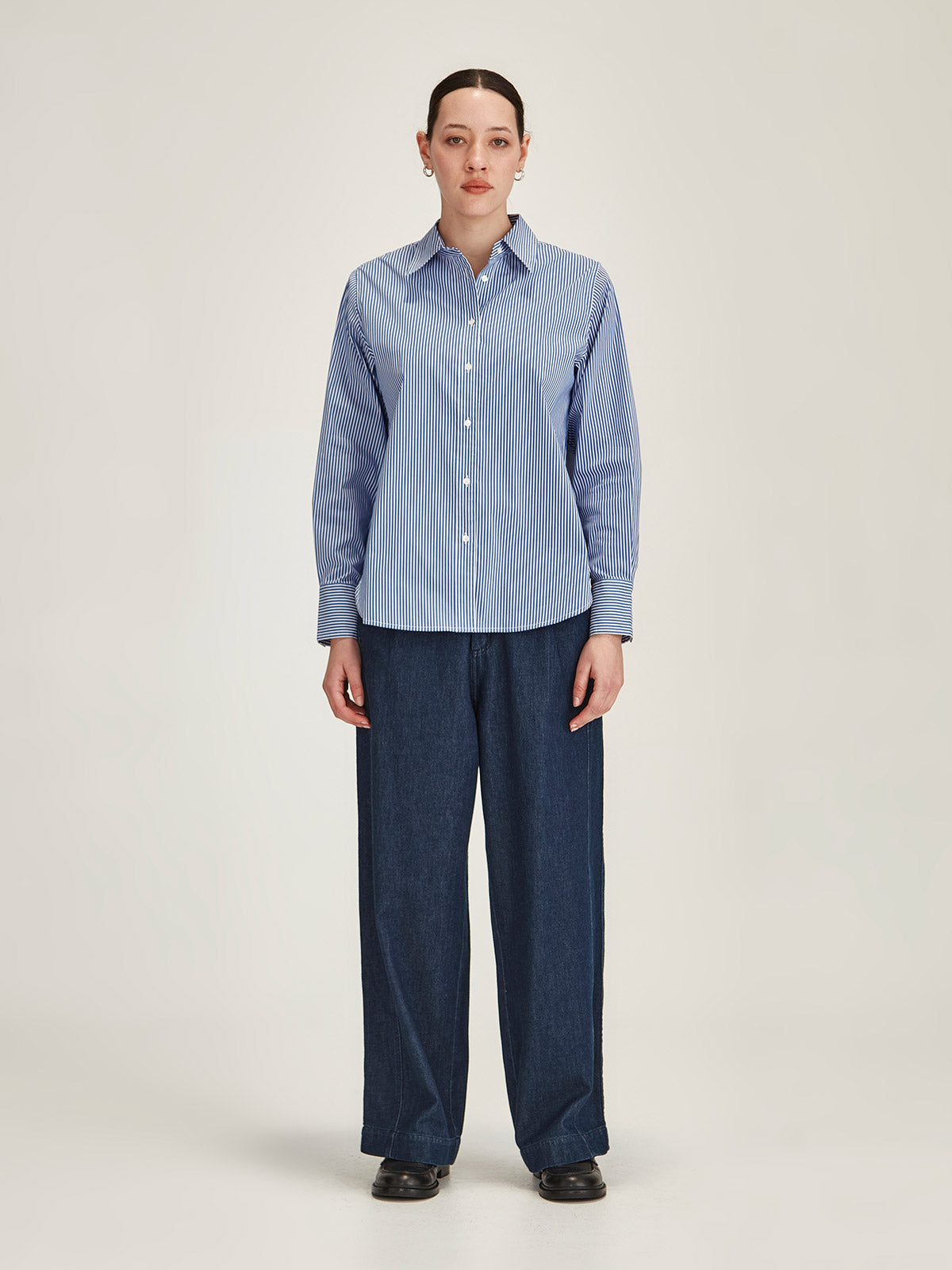 woman wearing navy Sills Princeton Striped button up Shirt and dark denim Britt Wide Leg Jeans against grey background
