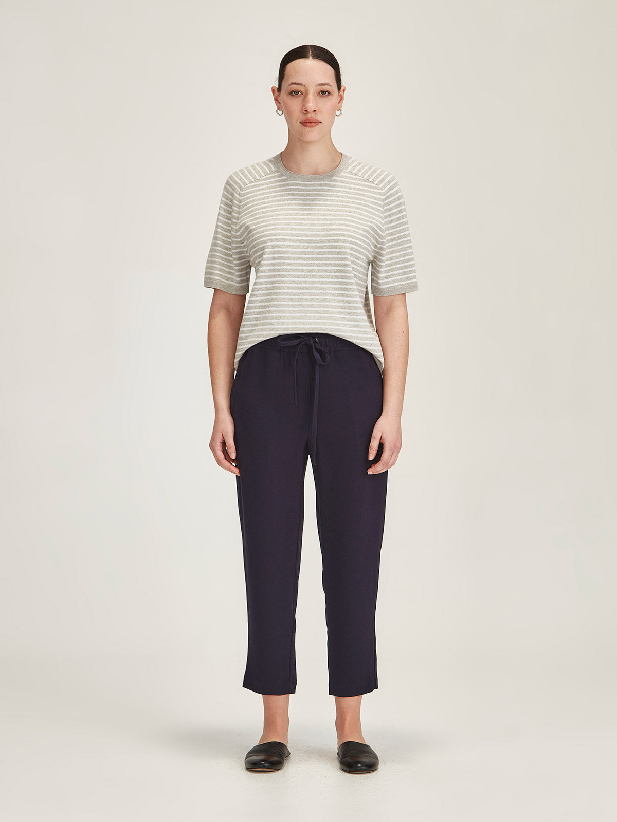 woman wearing Sills Cecilia striped knitted t-shirt and Joseph navy cropped pant on grey background