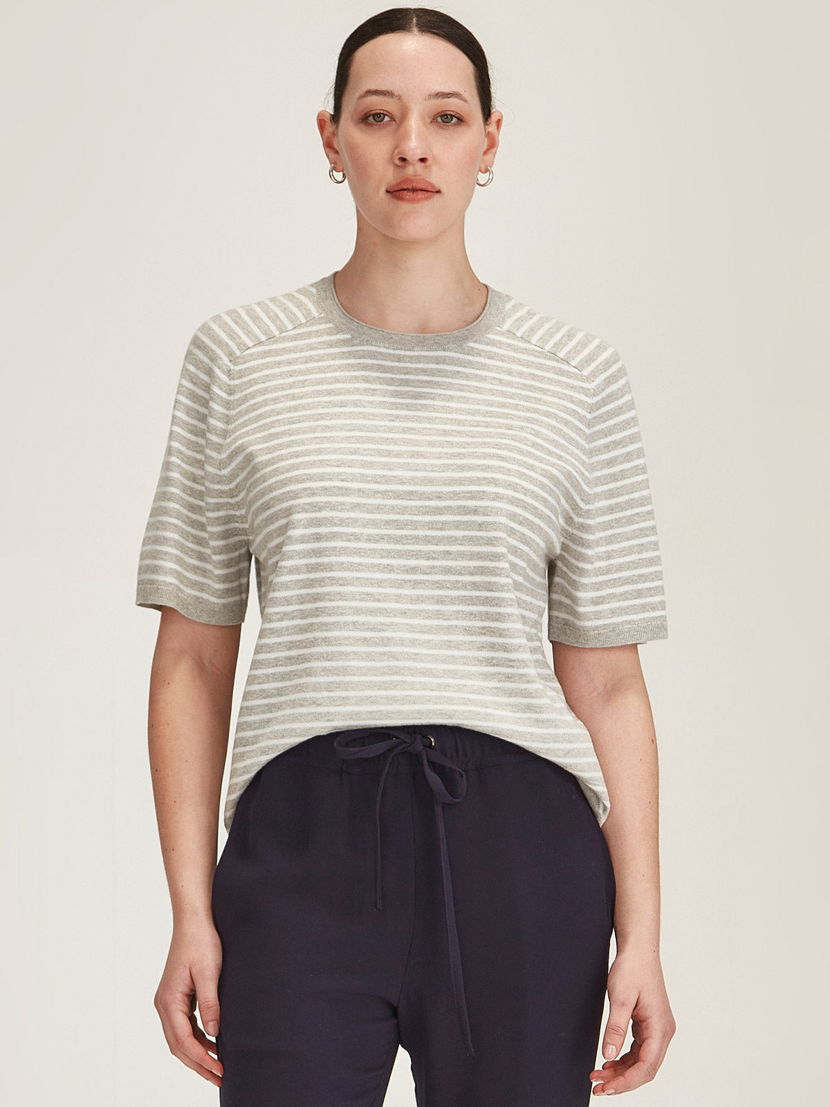 woman wearing Sills Cecilia Stripe knitted Tee t-shirt in off white and grey stripe on grey background
