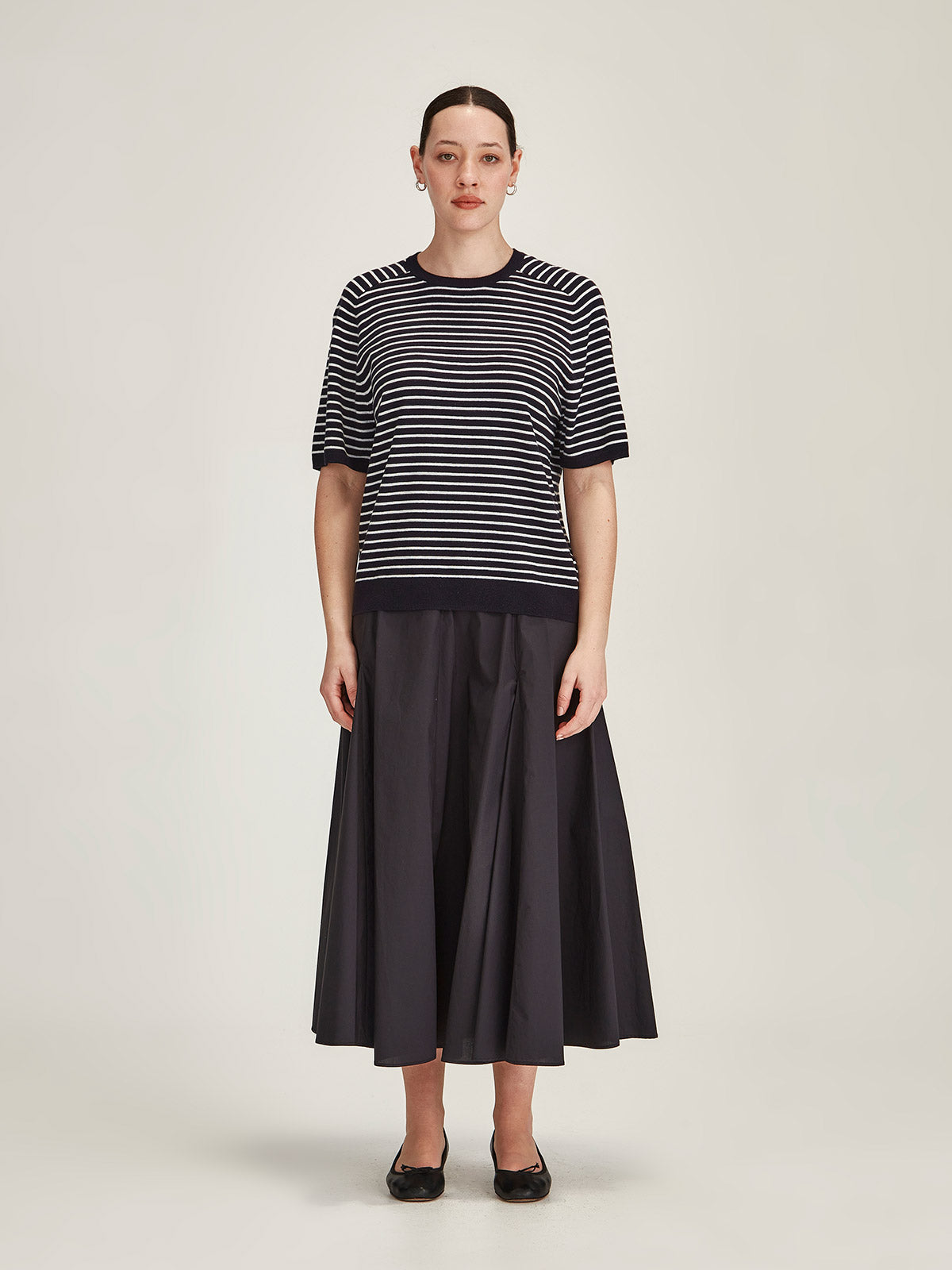 woman wearing Sills Cecilia striped knitted t-shirt and navy Zaiya midi skirt on grey background
