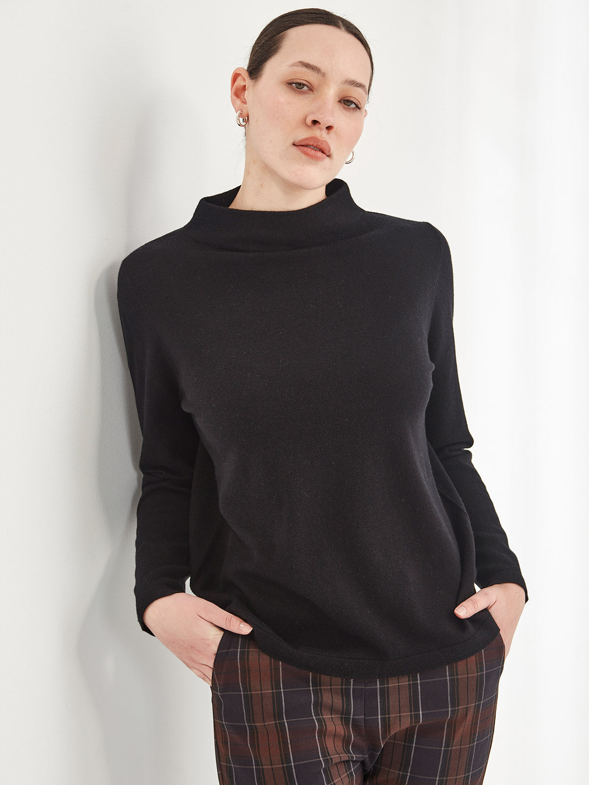 close up of woman wearing black Sills Tasmin funnel neck sweater against white background