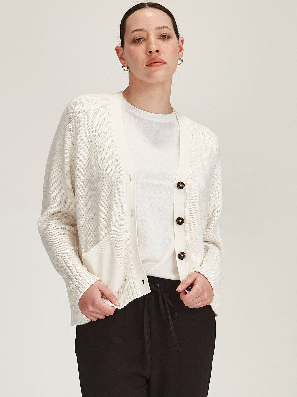 close up of woman wearing Sills off white knitted merino/cotton Yuri Cardigan against grey background