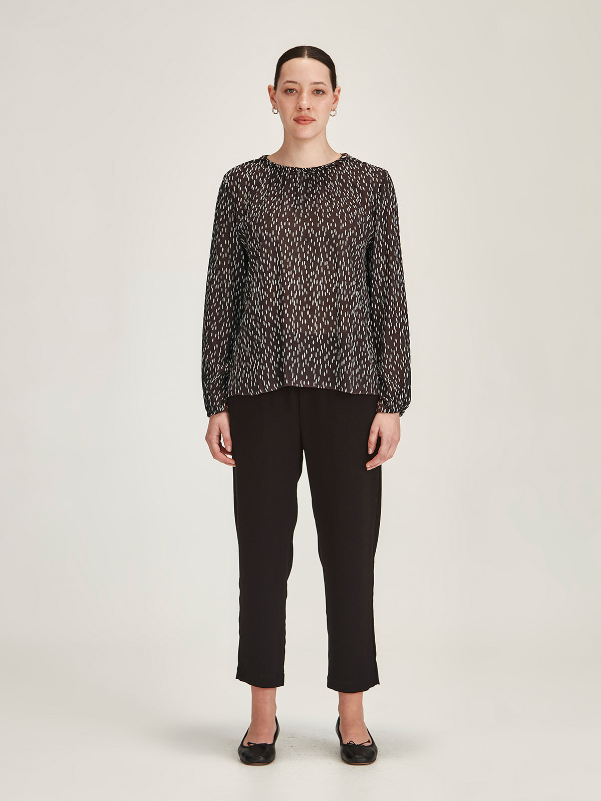 woman wearing Sills cocoa Anna Spot polka dot crepe blouse Top with black Romily cropped Pant against grey background