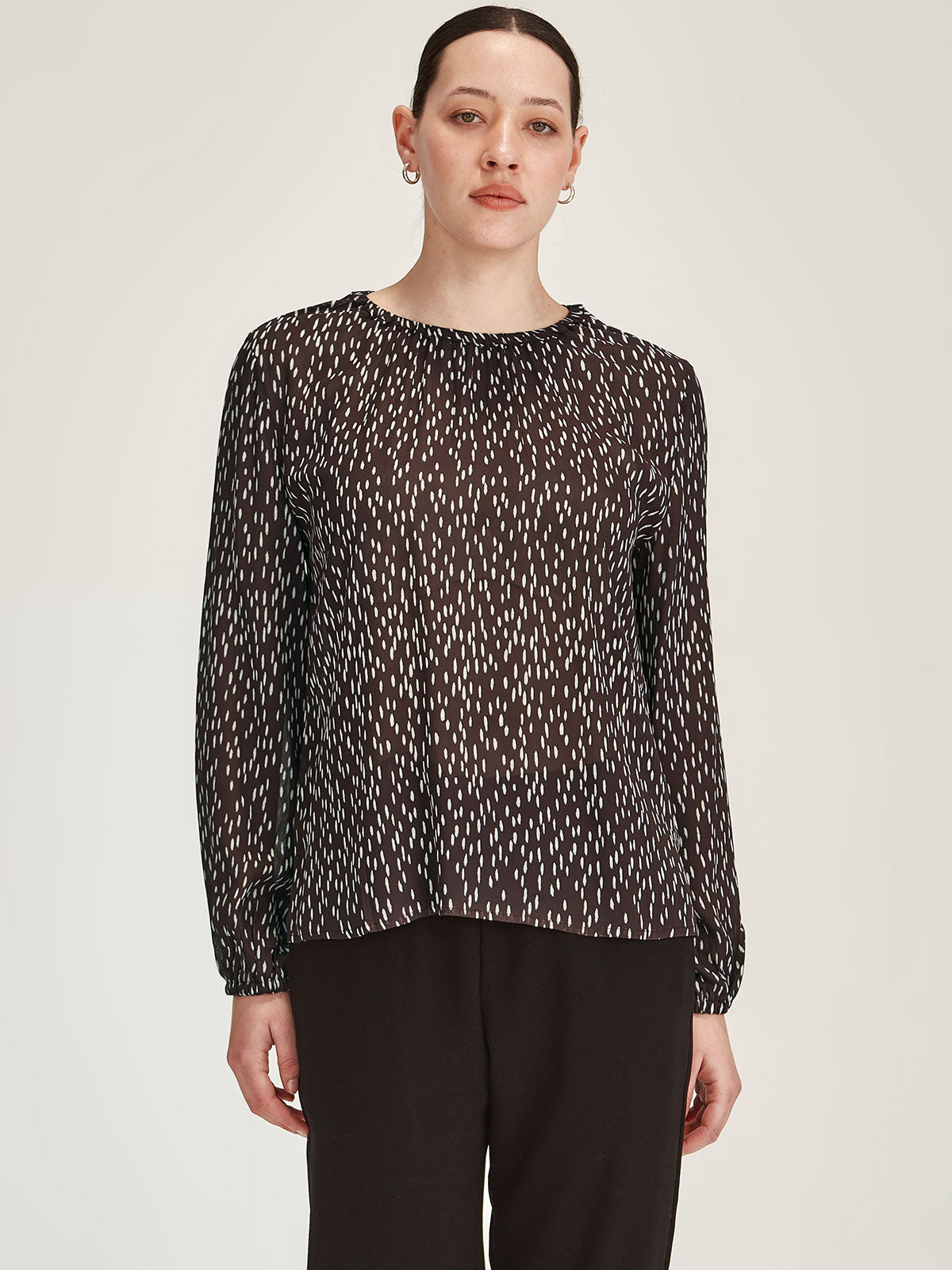 close up of woman wearing Sills Anna Spot polka dot crepe blouse Top in Cocoa brown against grey background