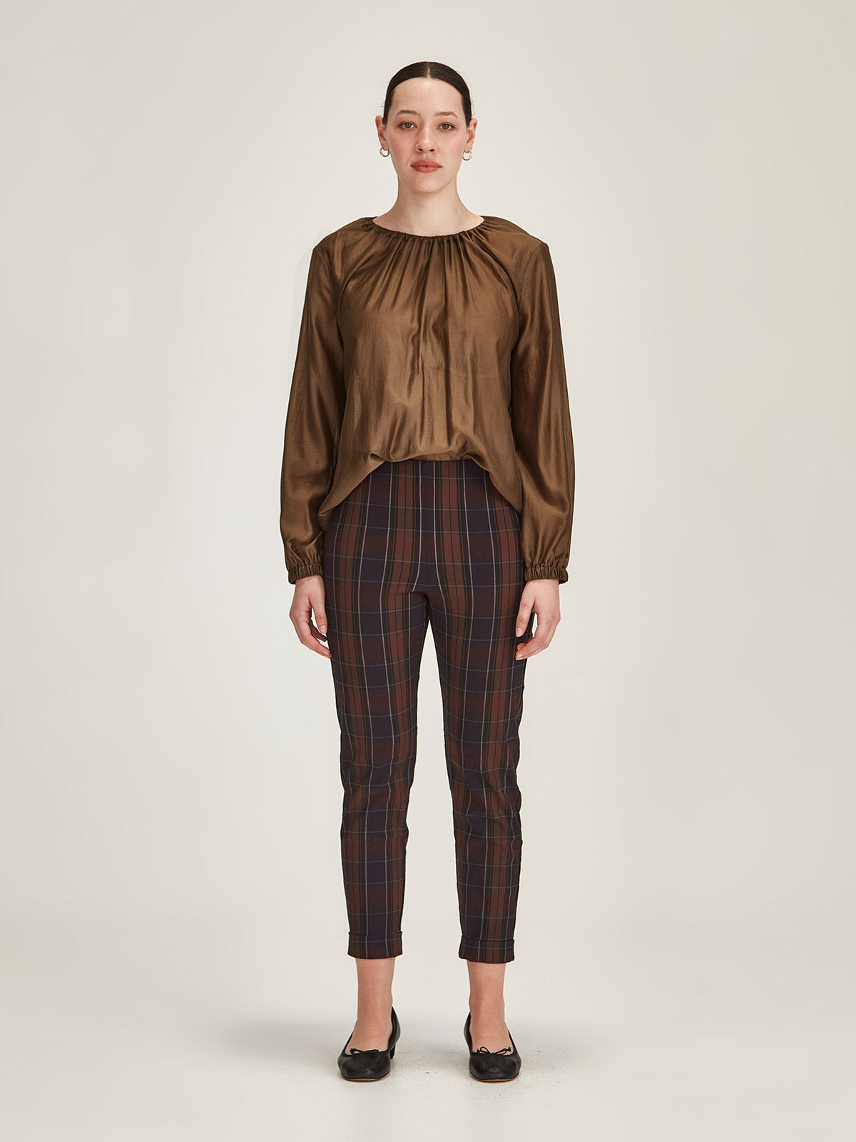 woman wearing Sills Anna chiffon blouse Top in Cinnamon with plaid pull-on Hepburn Pant against grey background