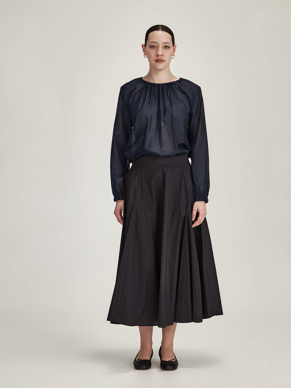 woman wearing Sills Anna chiffon blouse Top in Navy with black Zaiya Godet midi Skirt against grey background