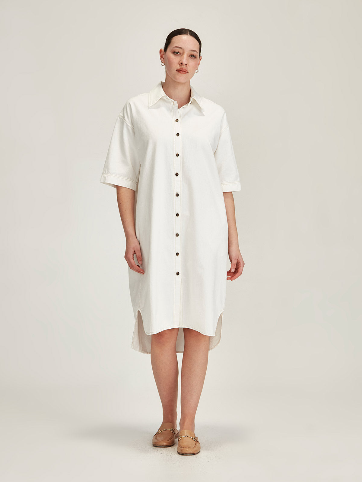 woman wearing white denim short sleeve Sills Alexa button-up shirt dress in front of grey background