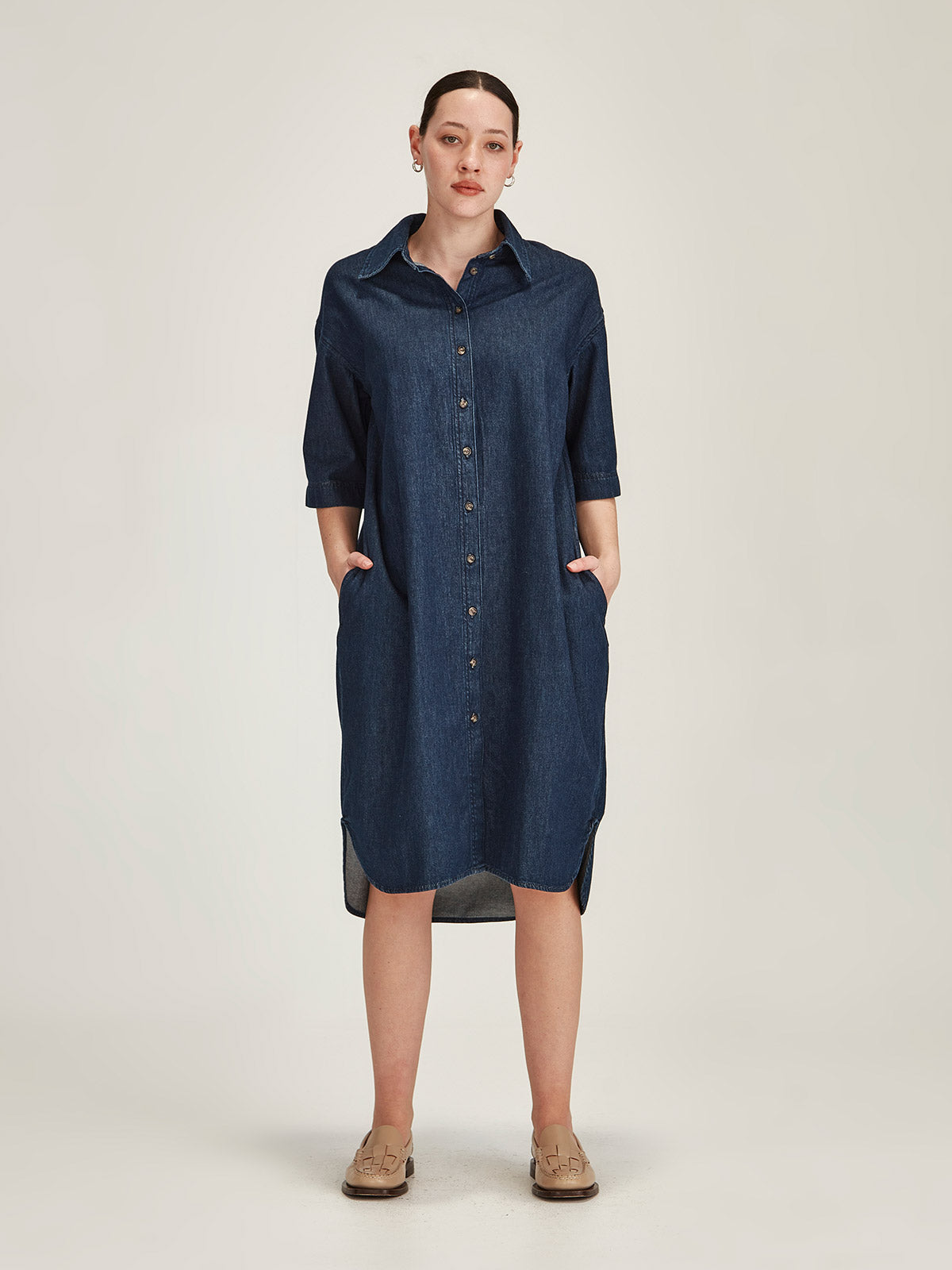 woman wearing dark denim short sleeve Sills Alexa button-up shirt dress in front of grey background
