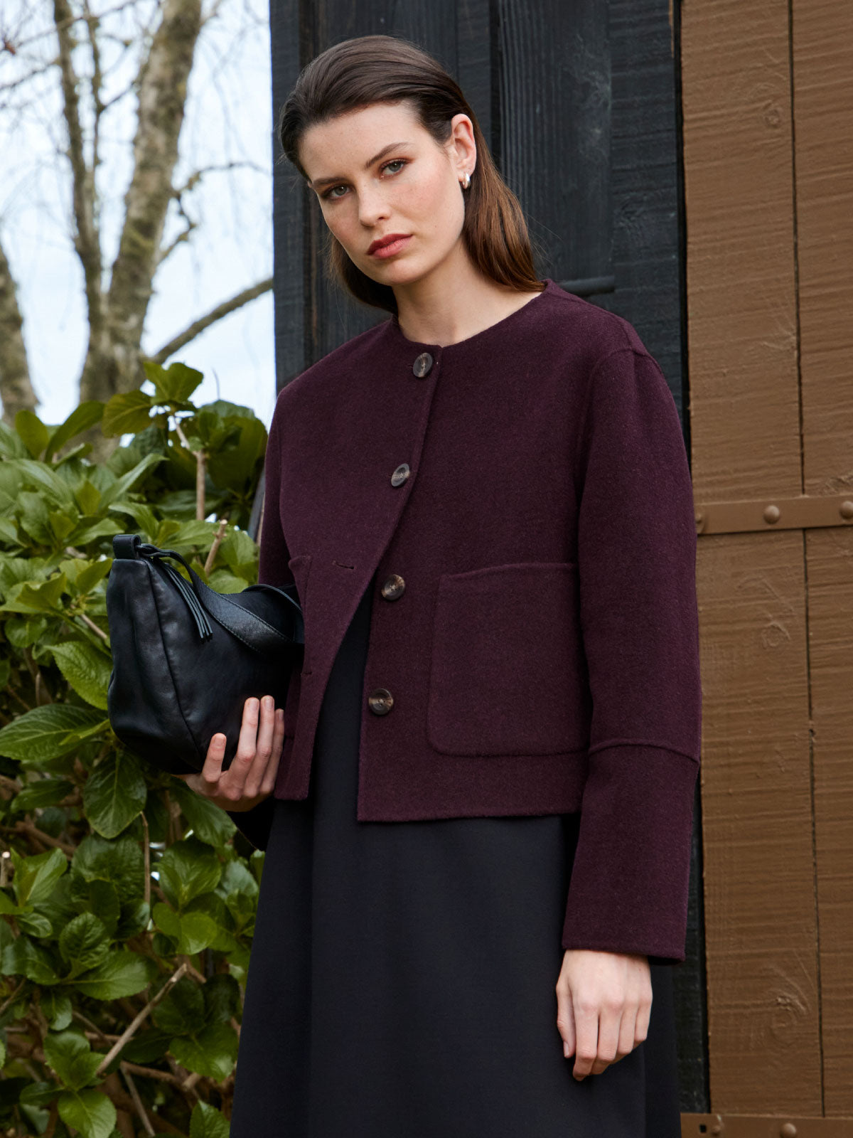 Woman outdoors wearing Sills Emiko wool and cashmere blend collarless Jacket in plum with Juju & Co Stevie Sling