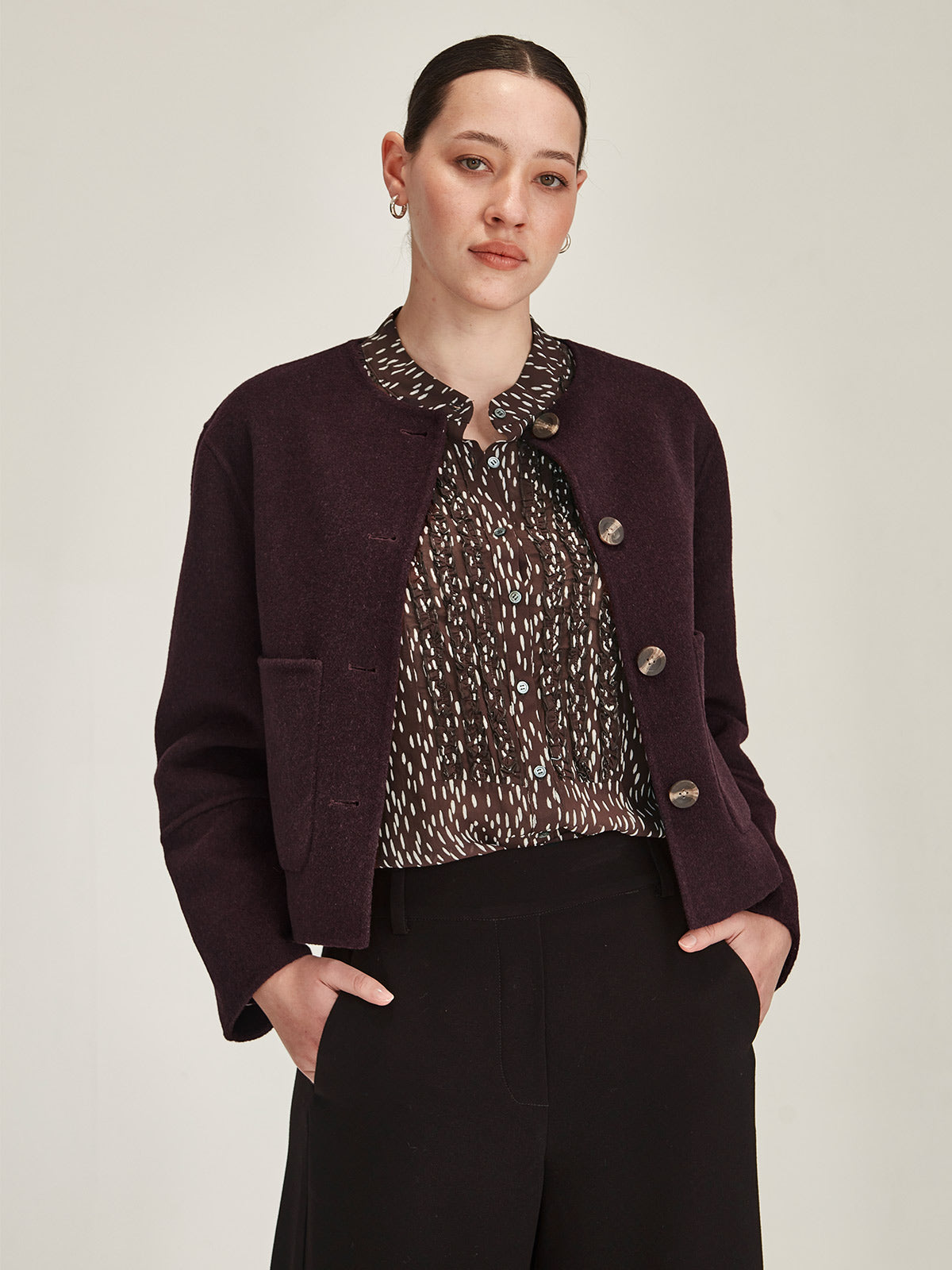 Close up of woman wearing Sills Plum Emiko wool and cashmere blend collarless Jacket on grey background