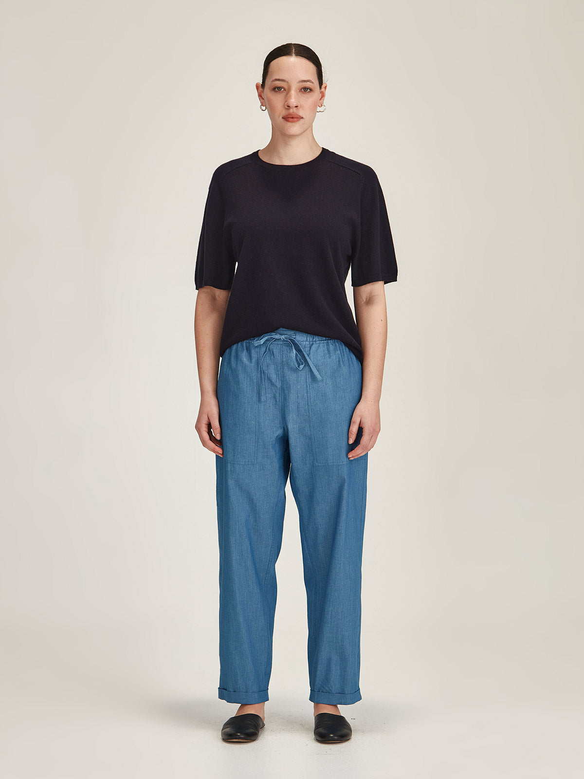 Woman in front of grey background wearing Sills Serena light indigo Chambray jogger Pant and navy Cecilia Knit Tee