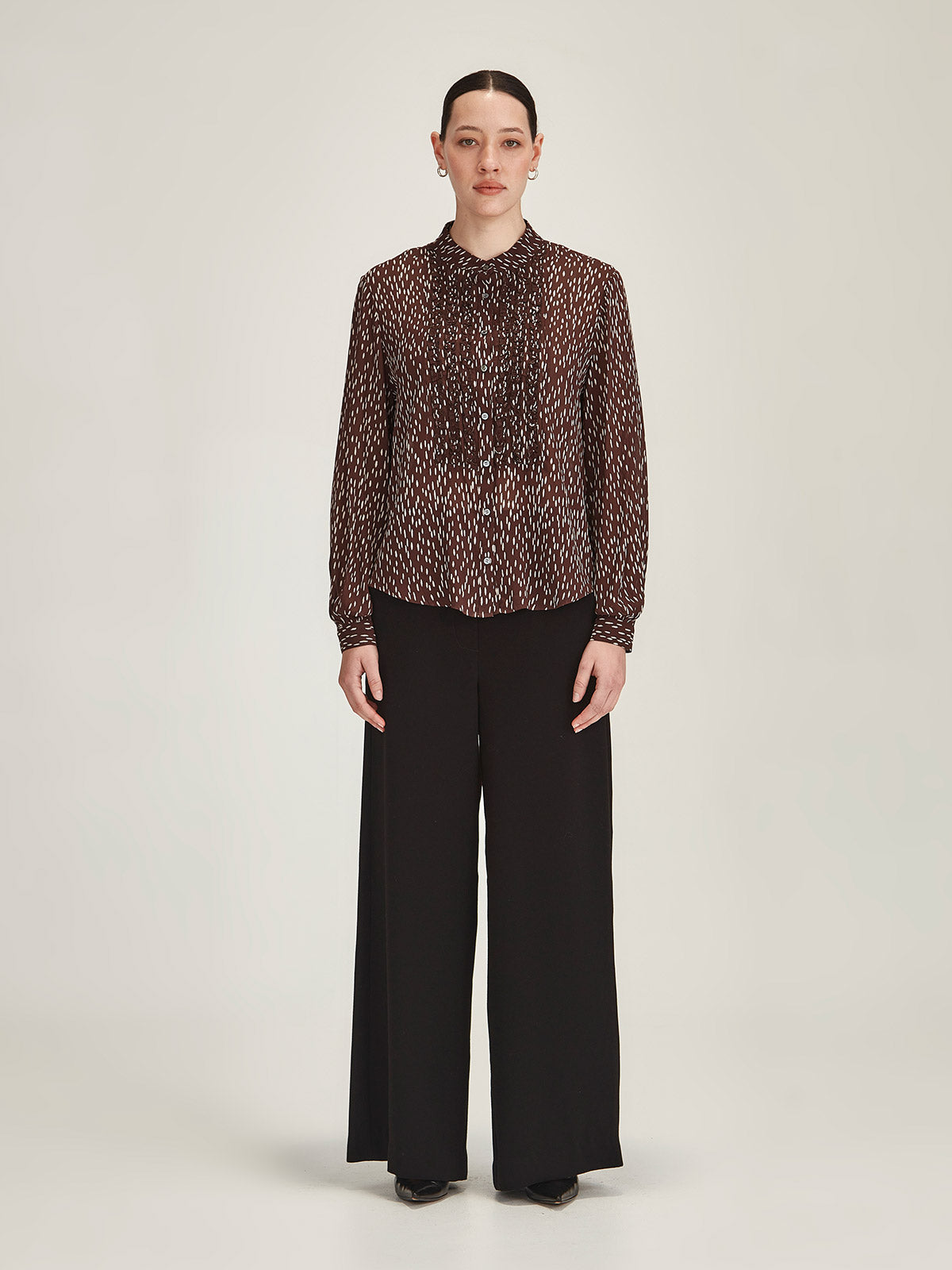 Woman wearing Sills black Luca Wide Leg crepe Pant with Ami Spot polka dot Shirt against grey background