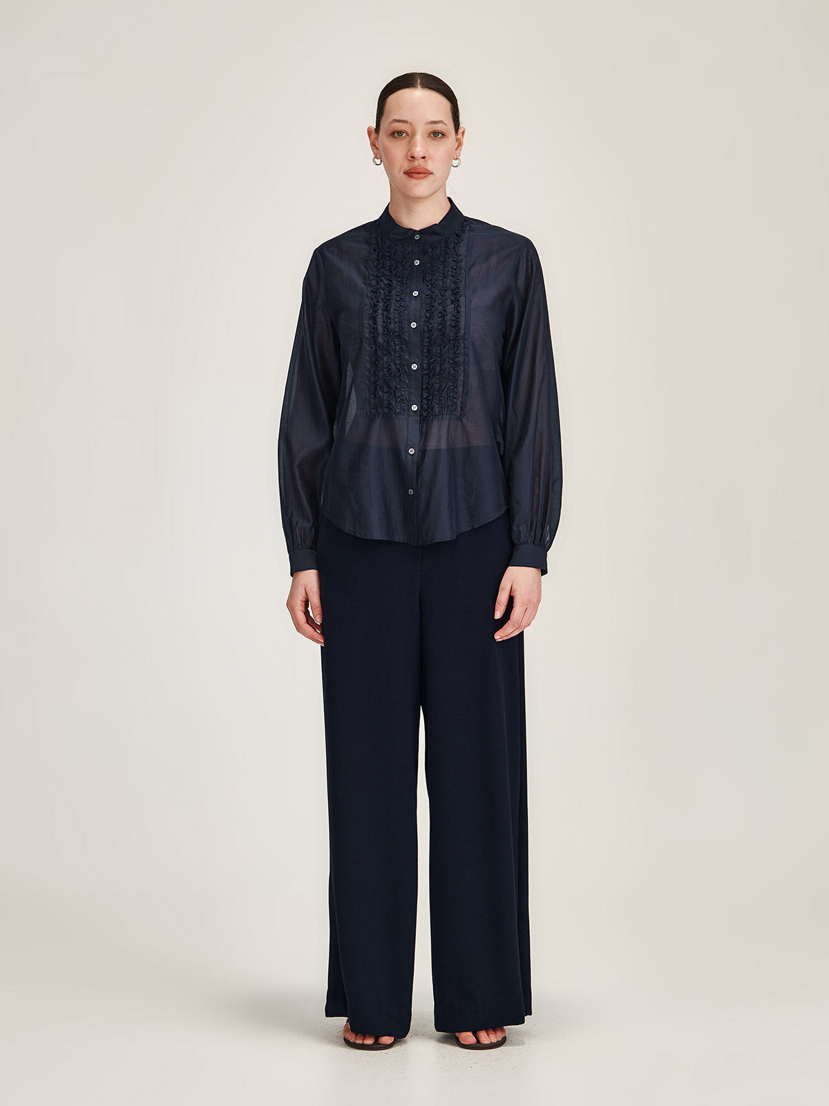 Woman wearing Sills navy Luca Wide Leg crepe Pant with Ami Ruffle chiffon Shirt against grey background
