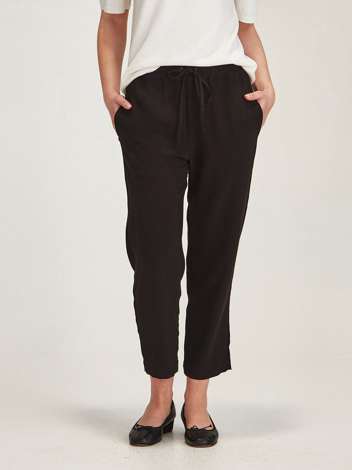 Close up of woman wearing Sills black Joseph crepe Romily cropped Pant on grey background