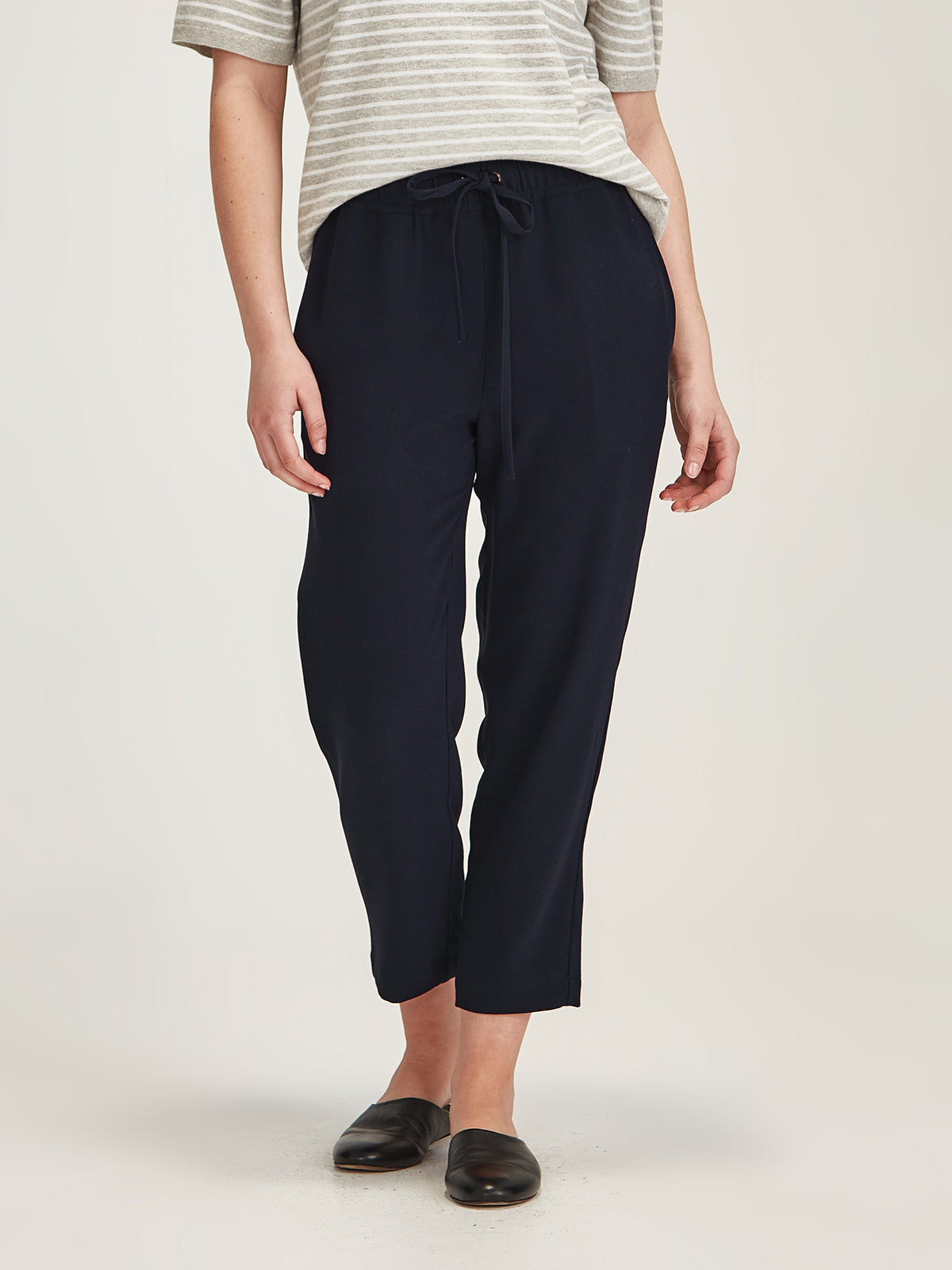 Close up of woman wearing Sills navy Joseph crepe Romily cropped Pant on grey background