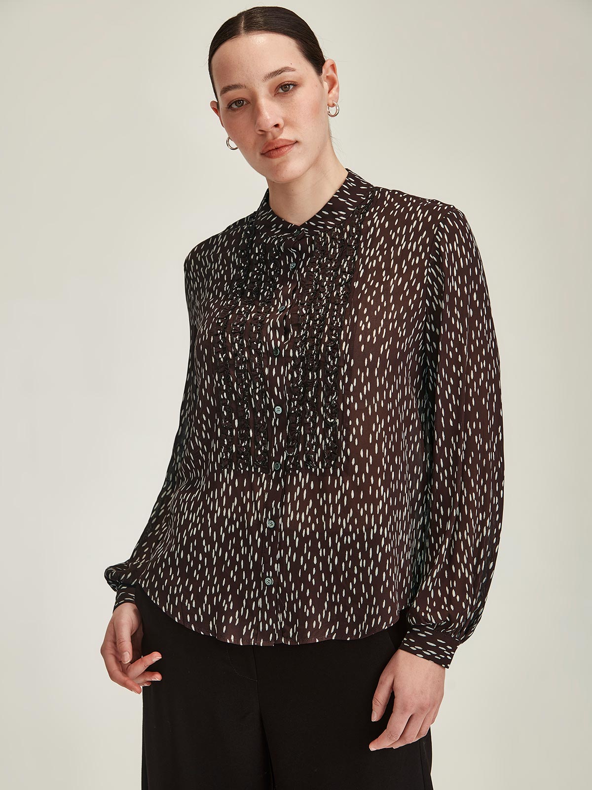 Close up of woman wearing cocoa brown Sills Ami Spot polka dot Shirt with ruffle detail front in front of grey background